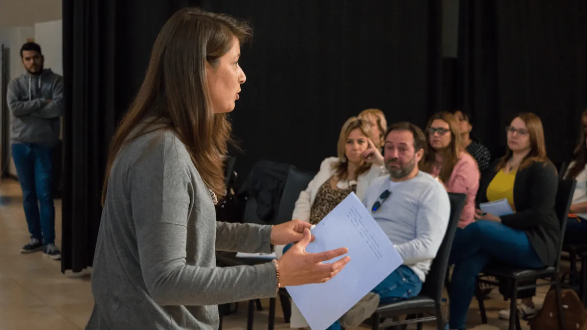 Una participante practica una exposición frente al grupo en un taller de oratoria